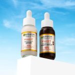 Garnier SkinActive Vitamin C brightening serum and night serum bottles on white pedestal against blue sky background