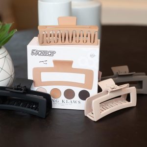 Assorted hair claw clips in various colours beside Framar packaging on a table