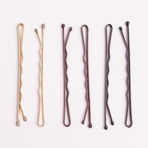 Set of gold, bronze, and black hairpins on white background, ideal for styling and securing hairstyles
